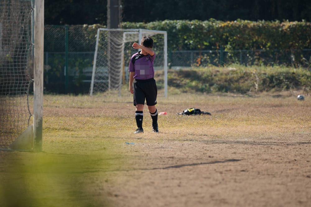 寂しそうに1人で歩くサッカー少年